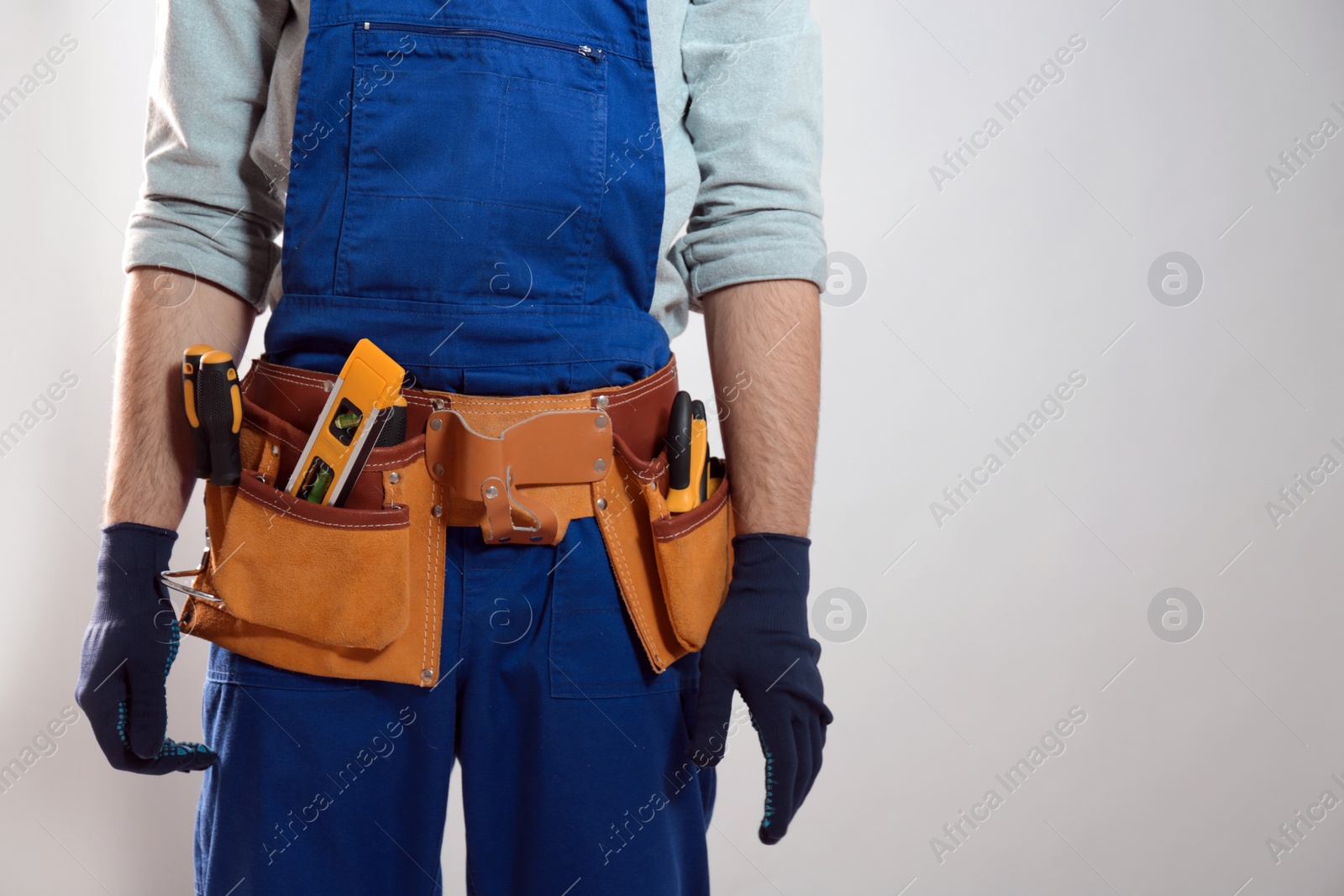 Photo of Construction worker with tool belt on light background, closeup. Space for text