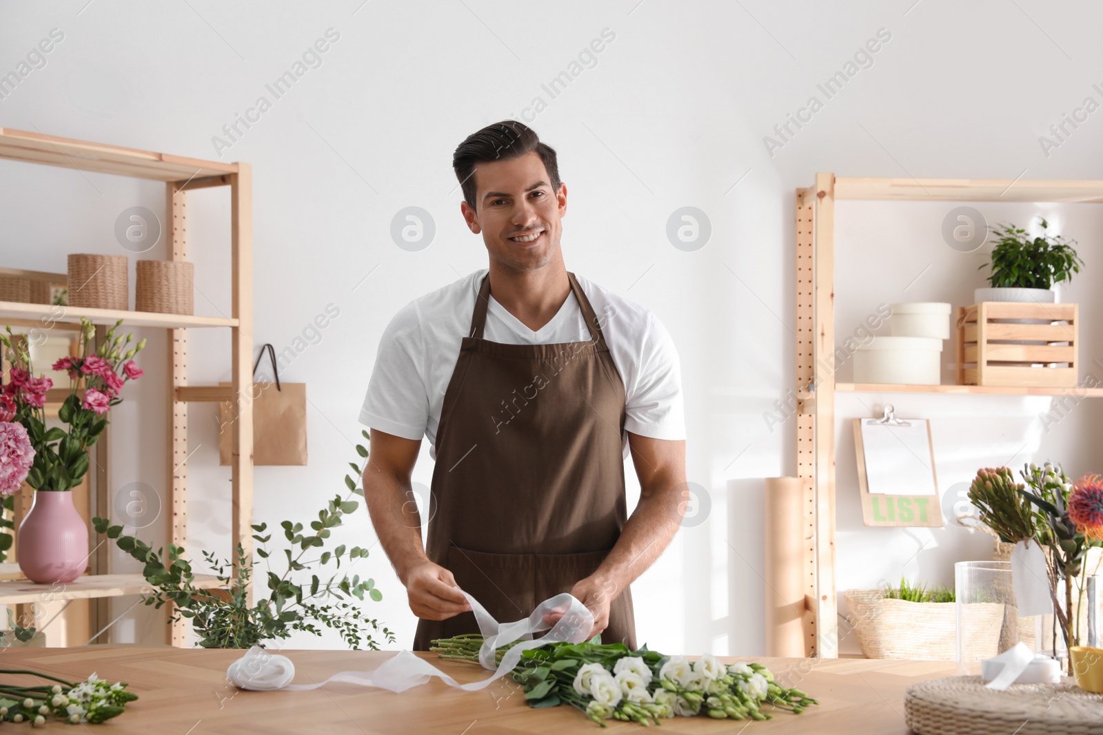 Photo of Florist making beautiful bouquet at table in workshop