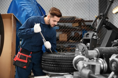 Technician working with car wheel at automobile repair shop