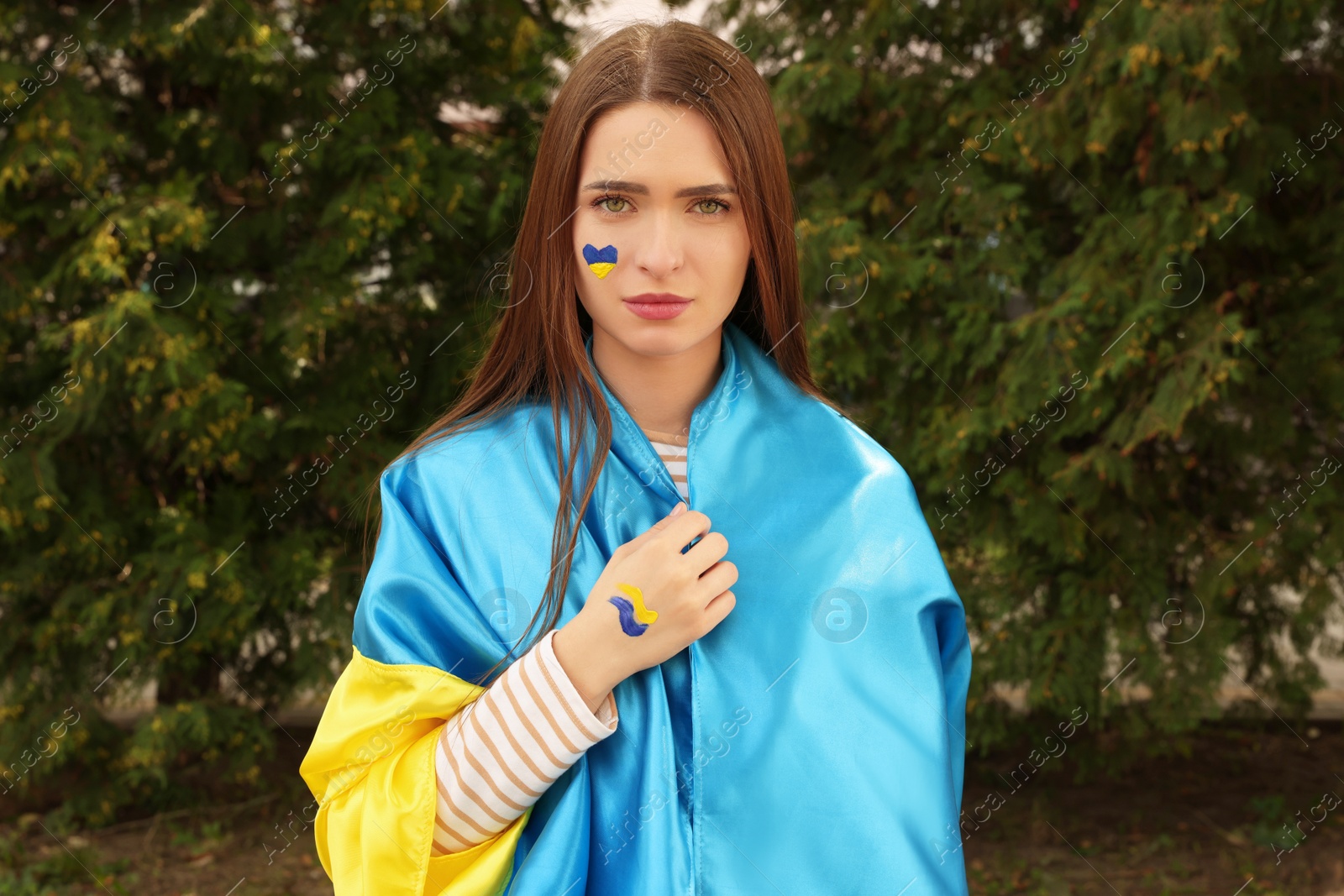 Photo of Young beautiful woman with Ukrainian flag outdoors