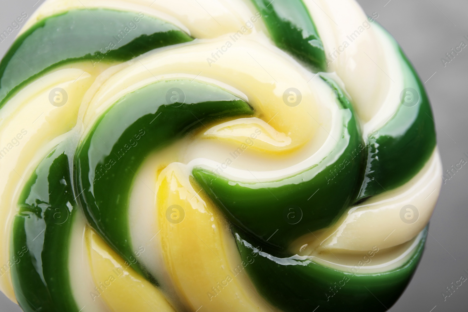 Photo of Colorful lollipop swirl on grey background, closeup