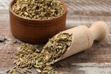 Photo of Bowl and scoop with fennel seeds on wooden table, closeup