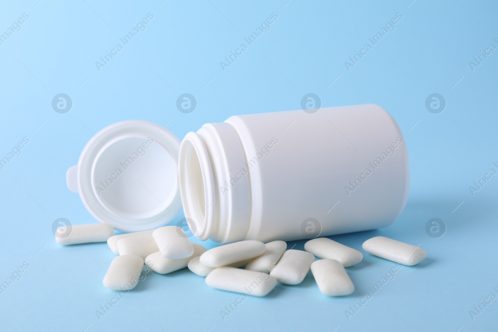 Photo of Jar with tasty chewing gums on light blue background