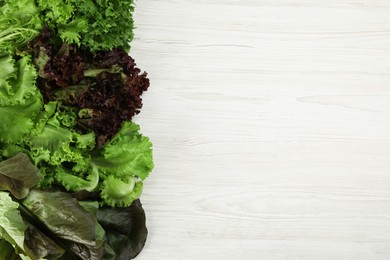 Photo of Different sorts of lettuce on white wooden table, flat lay. Space for text