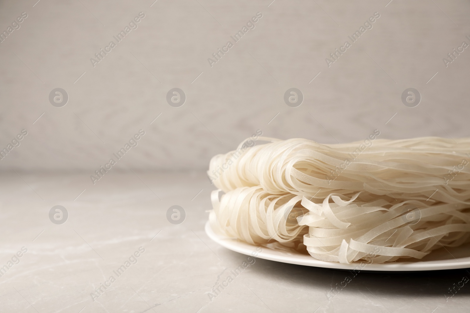 Photo of Plate with raw rice noodles on table, closeup. Space for text