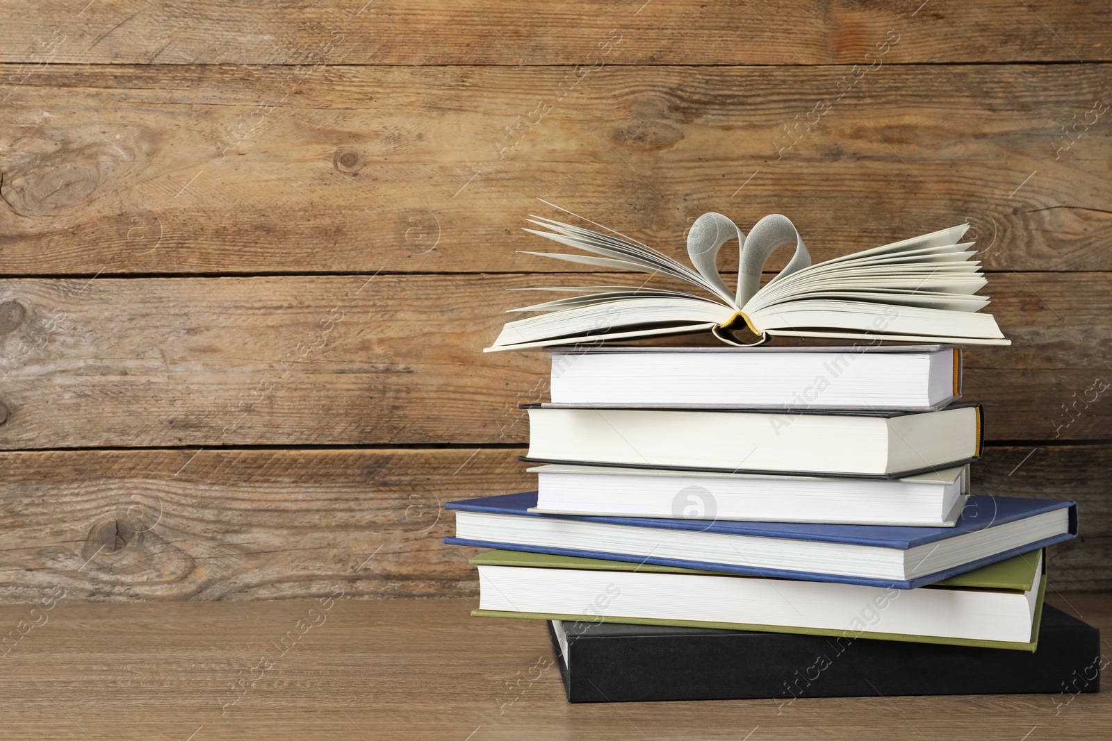 Photo of Stack of hardcover books on wooden table, space for text