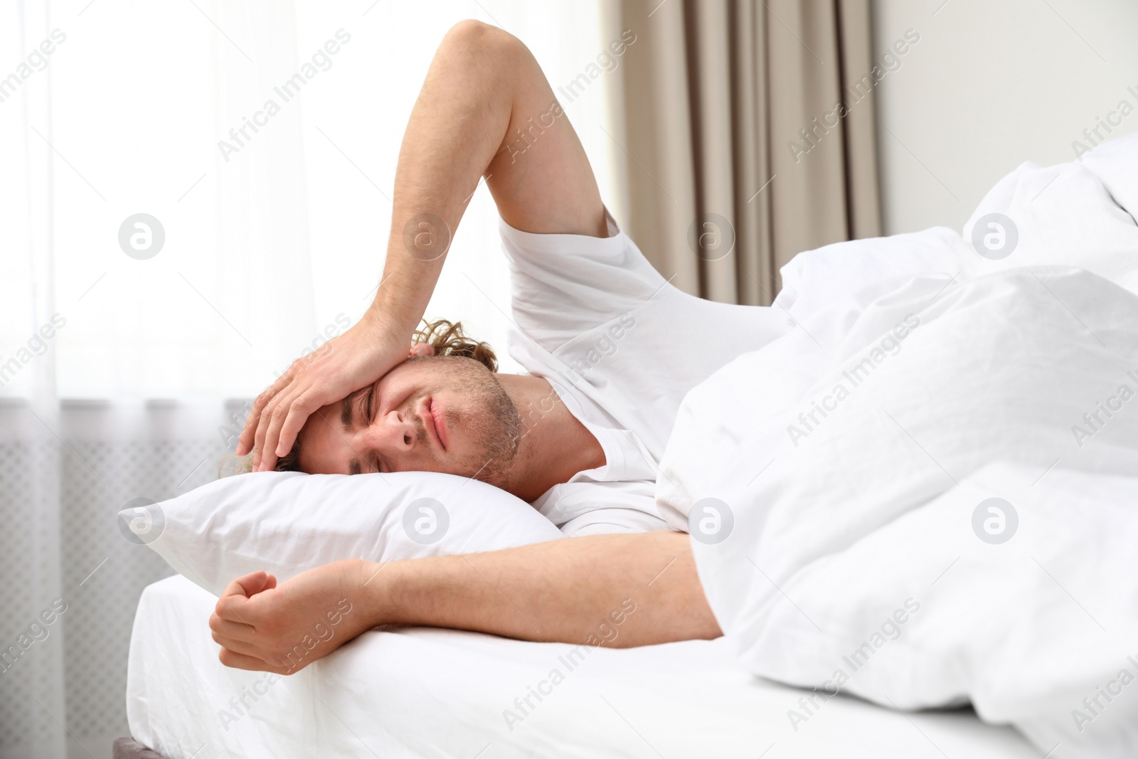 Photo of Sleepy young man lying on pillow at home. Bedtime