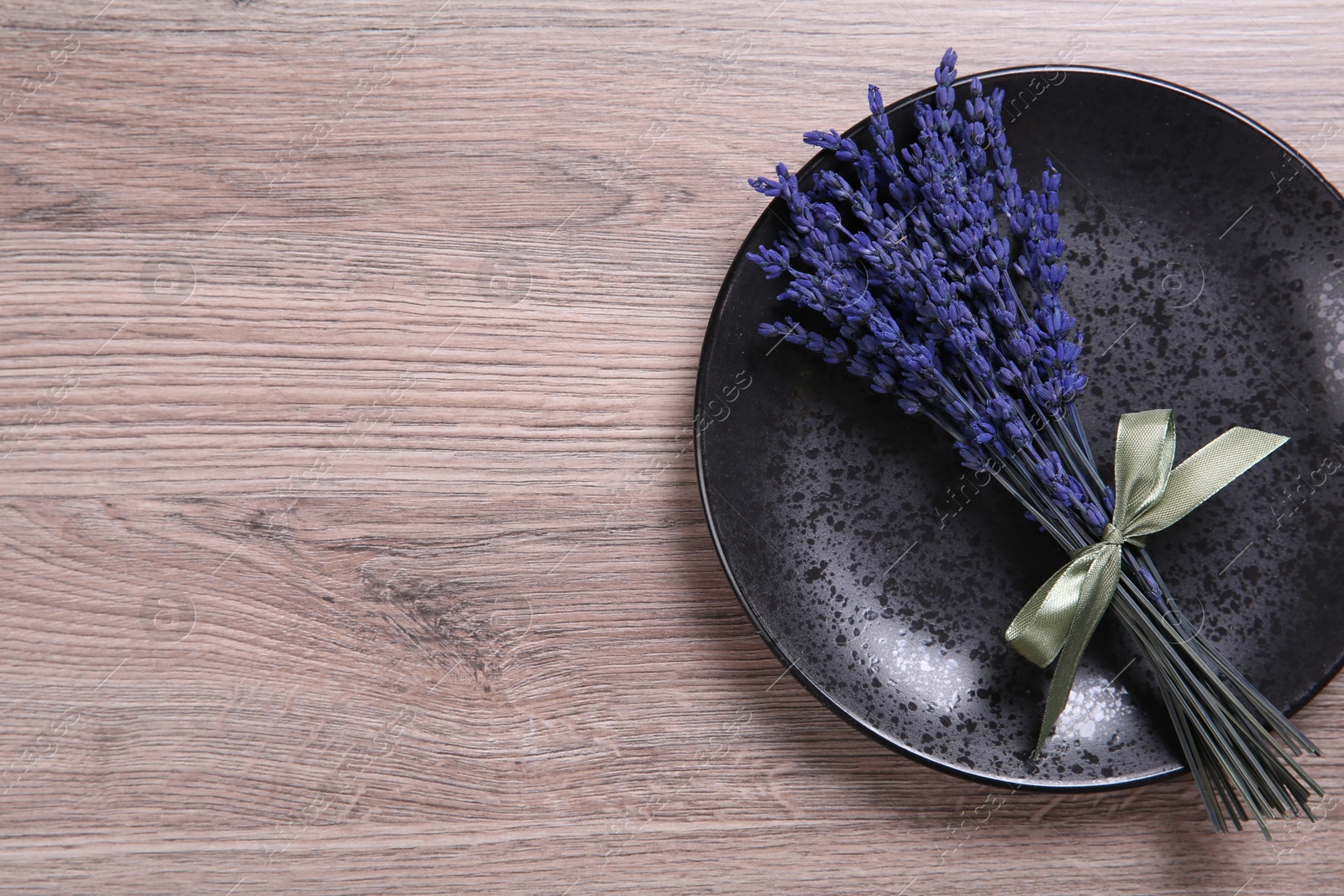 Photo of Bouquet of beautiful preserved lavender flowers and plate on wooden table, top view. Space for text