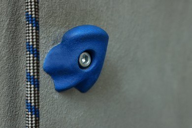 Climbing wall with hold and rope, closeup. Space for text