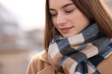 Beautiful woman in warm scarf outdoors, space for text