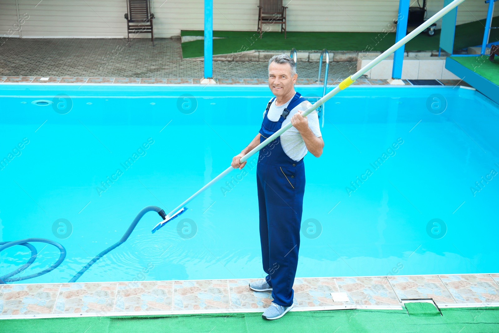 Photo of Male worker cleaning outdoor pool with underwater vacuum