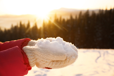 Woman holding pile of snow outdoors, closeup. Winter vacation