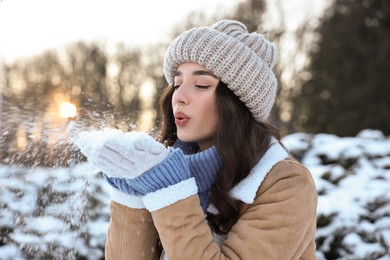 Photo of Portrait of beautiful woman blowing snow from hands in park