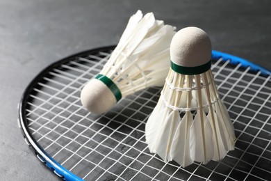 Photo of Feather badminton shuttlecocks and racket on grey textured table, closeup