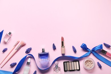 Flat lay composition with different makeup products and beautiful spring flowers on pink background. Space for text