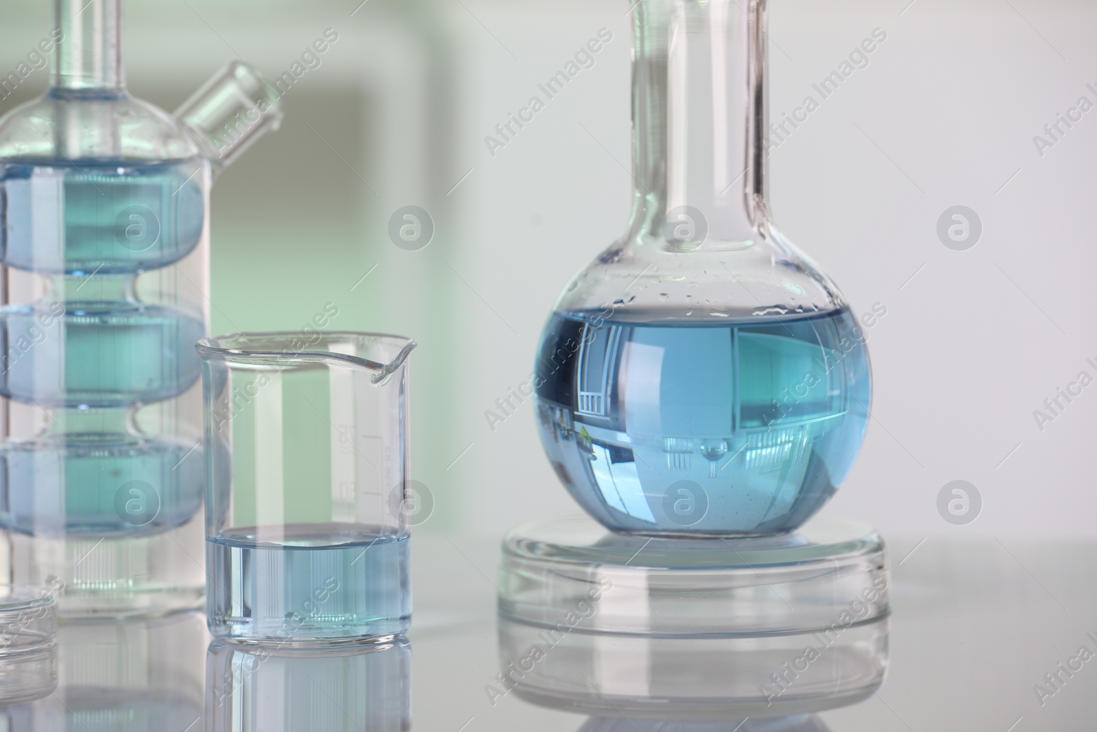 Photo of Laboratory analysis. Different glassware with liquid on white table against blurred background, closeup