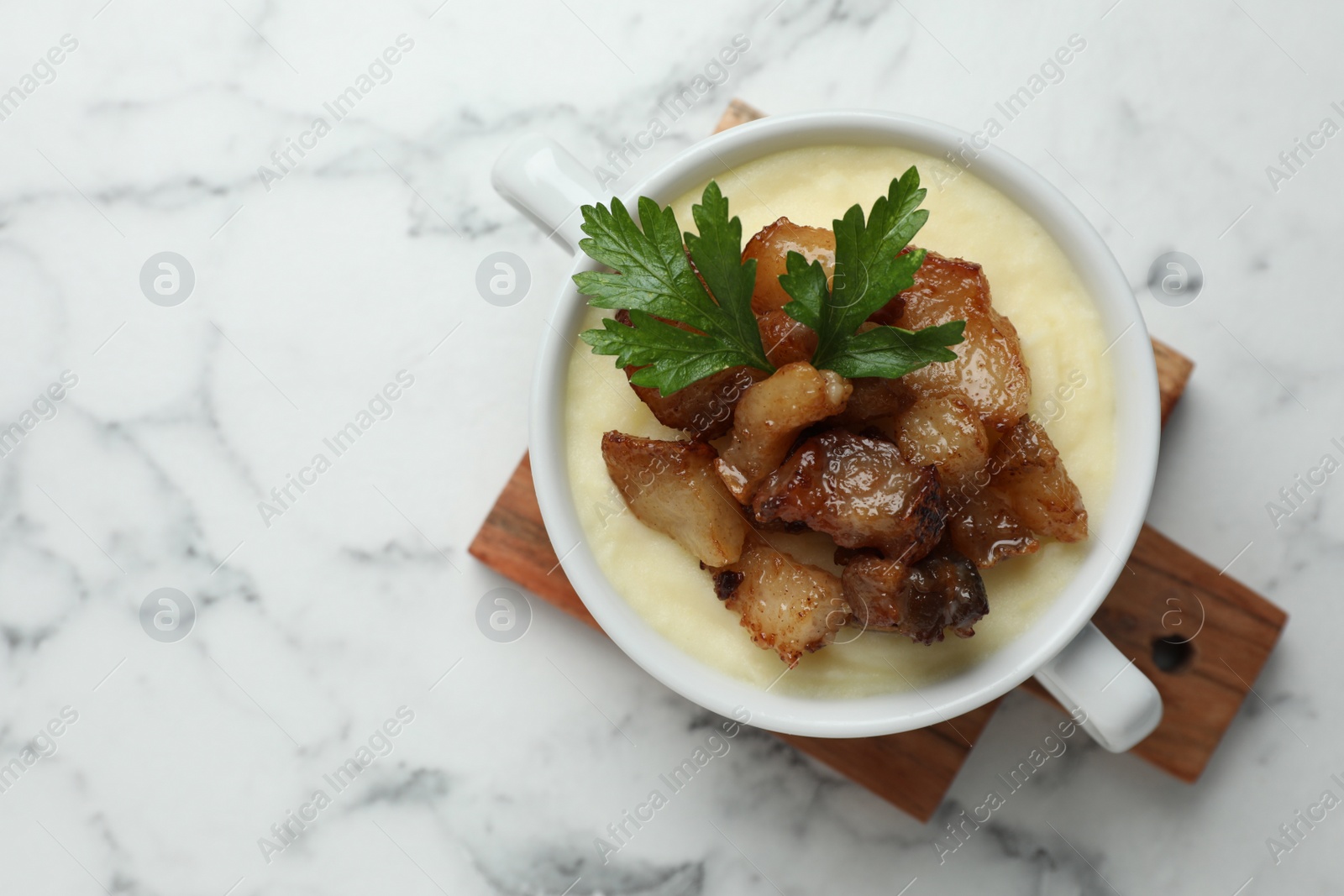 Photo of Potato puree and tasty fried cracklings on white marble table, top view with space for text. Cooked pork lard