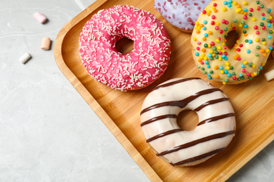 Photo of Yummy donuts with sprinkles on marble table, flat lay