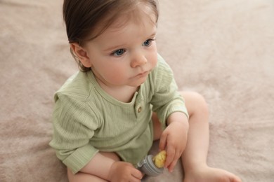 Cute baby girl with nibbler on beige blanket