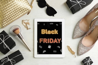 Photo of Flat lay composition with tablet, gifts and accessories on white table. Black Friday sale