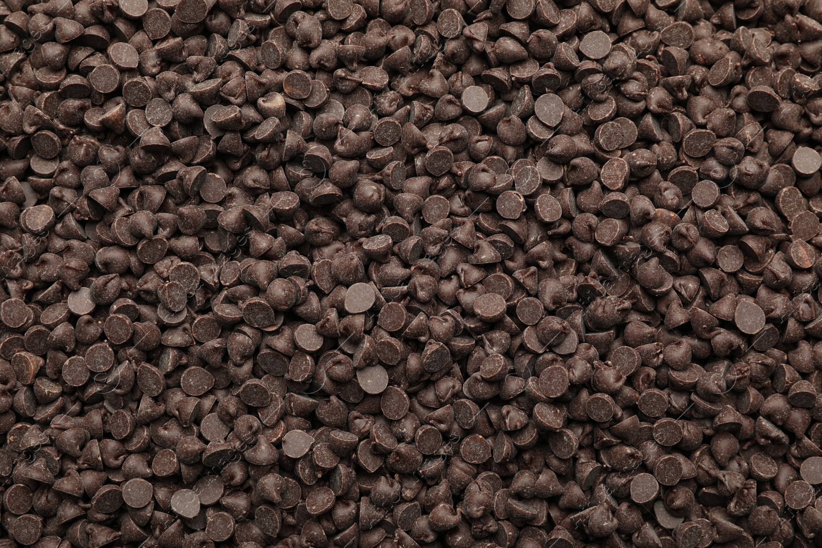 Photo of Delicious chocolate chips as background, top view