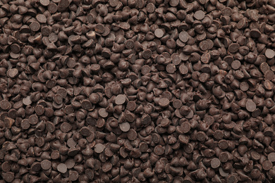 Photo of Delicious chocolate chips as background, top view