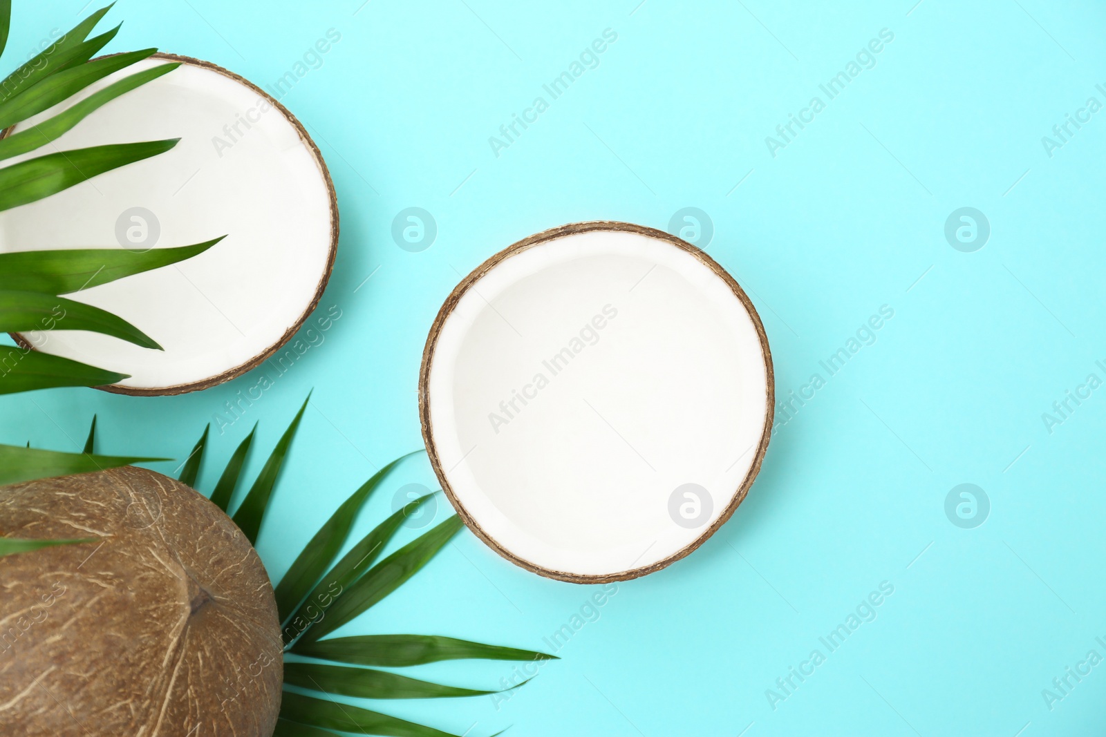 Photo of Fresh coconuts and palm leaves on light blue background, flat lay