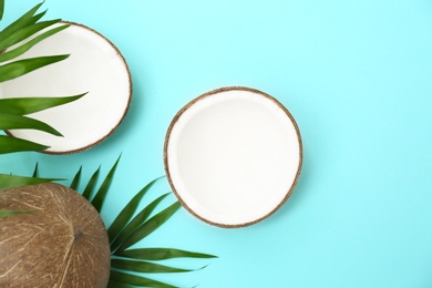 Photo of Fresh coconuts and palm leaves on light blue background, flat lay