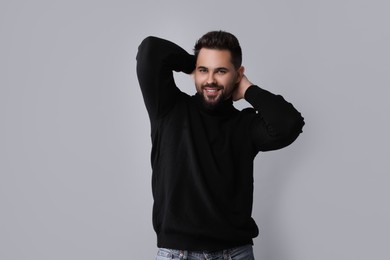 Photo of Happy man in stylish black sweater on grey background