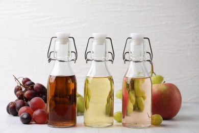 Different types of vinegar and ingredients on light tiled table, closeup