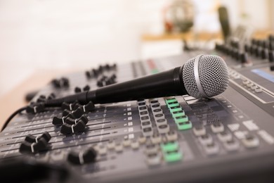 Photo of Microphone on professional mixing console in modern radio studio, closeup