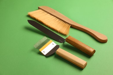 Photo of Three different beekeeping tools on green background