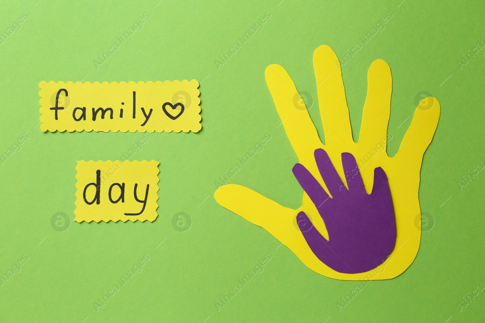 Photo of Paper palms and cards with text Family Day on light green background, flat lay