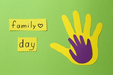 Photo of Paper palms and cards with text Family Day on light green background, flat lay