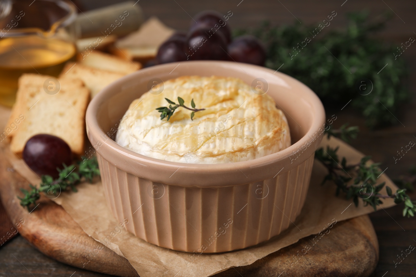 Photo of Tasty baked camembert in bowl on table, closeup