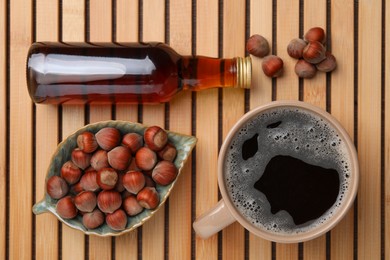 Photo of Mug of aromatic coffee, syrup and hazelnuts on wooden table, flat lay