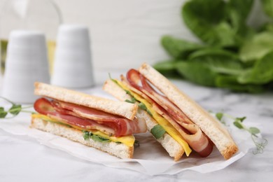 Delicious sandwiches with bacon on white table, closeup