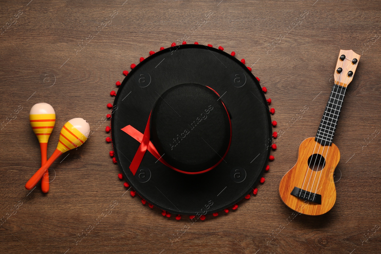 Photo of Mexican sombrero hat, maracas and guitar on wooden background, flat lay