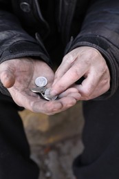 Poor homeless man holding coins outdoors, closeup