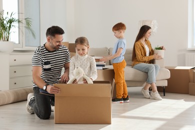Photo of Happy family unpacking boxes in new apartment. Moving day