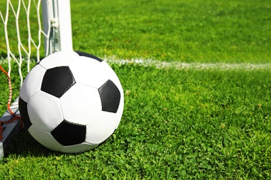 Photo of Soccer ball near net on green football field grass. Space for text