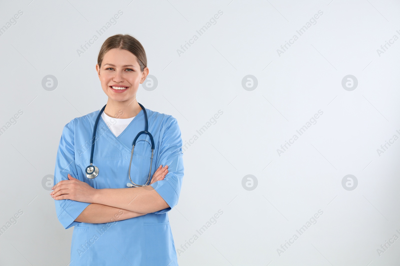 Photo of Young doctor with stethoscope against light background