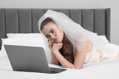 Upset bride with laptop on bed in bedroom