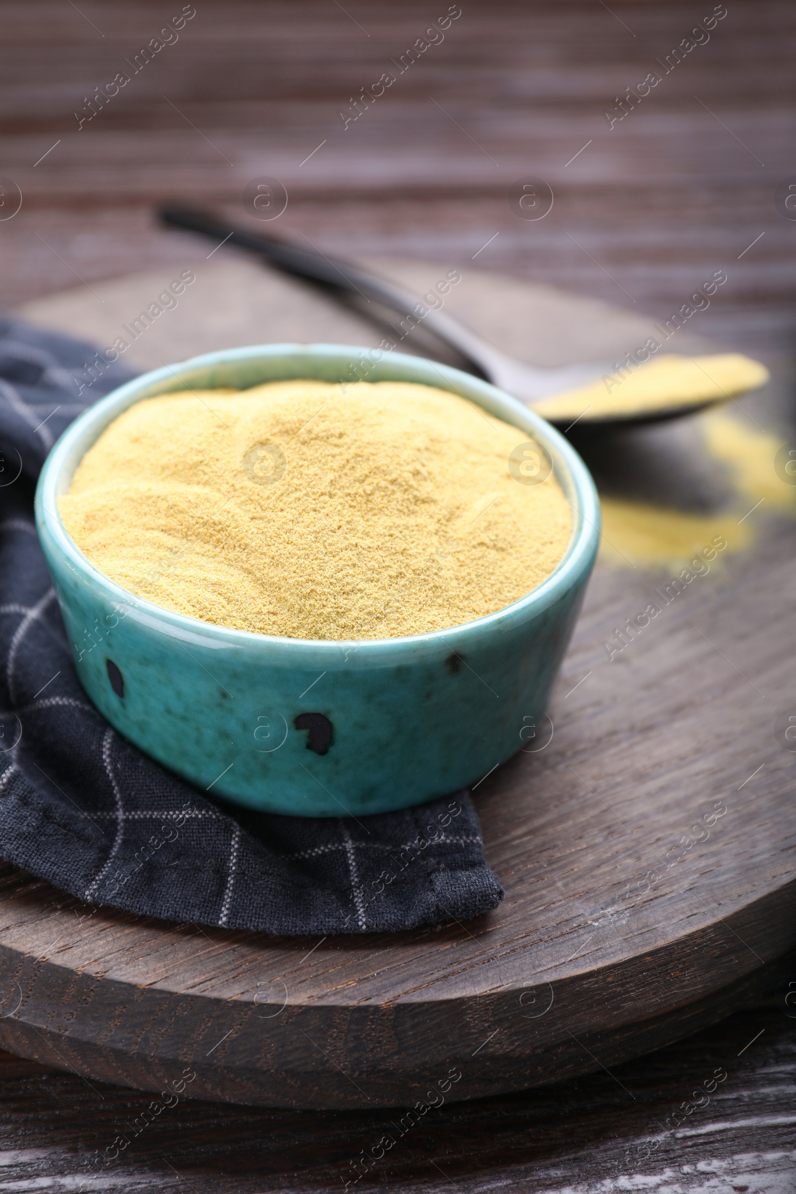 Photo of Granulated brewer`s yeast in bowl on wooden table