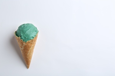 Delicious spirulina ice cream in waffle cone on white background, top view