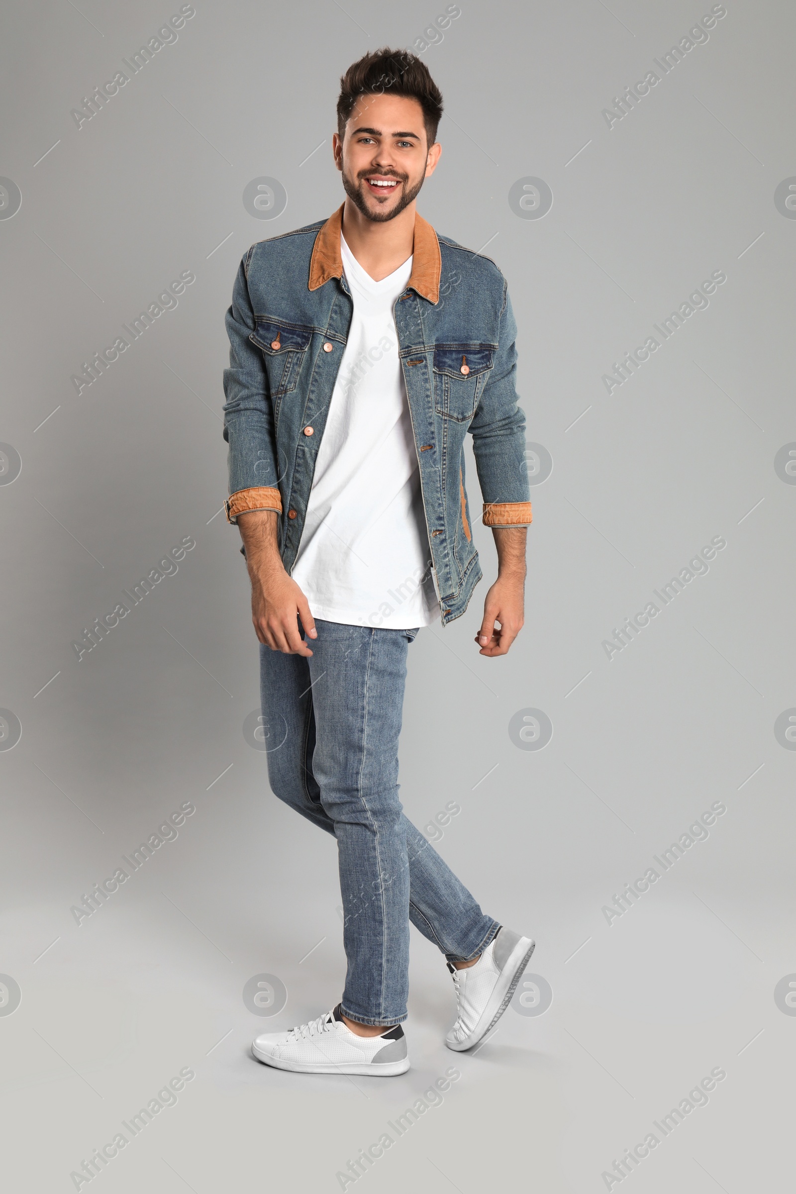 Photo of Young man in stylish jeans on grey background