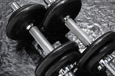 Photo of Two barbells on dark textured floor, closeup