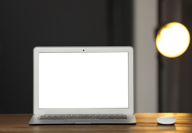 Laptop with blank screen on table indoors. Space for text