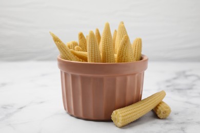 Photo of Bowl and pickled baby corn on white marble table