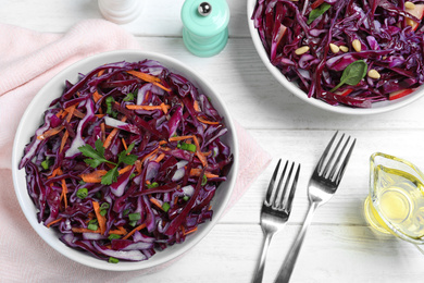 Photo of Fresh red cabbage salad served on white wooden table, flat lay